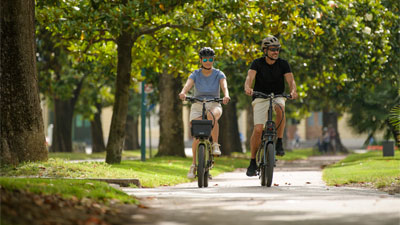 Un hombre y una mujer van en bicicletas plegables por un parque.