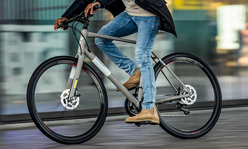 Un ciclista recorre la ciudad con su bicicleta de fitness, solo se le ve parcialmente.
