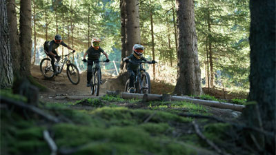 Dos jóvenes y un ciclista recorren el bosque en bicicletas de montaña Cube Stereo MTB DE DOBLE SUSPENSIÓN.