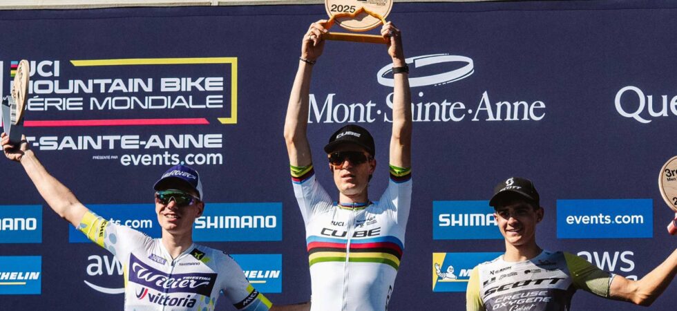 Finn Treudler celebra en la final de temporada del Cube Factory Racing 2025 en Mont-Sainte-Anne, sosteniendo el trofeo en sus manos, flanqueado por los ciclistas que ocuparon el segundo y tercer lugar en el podio.