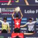 Finn Treudler celebra en el podio, levantando con orgullo el trofeo por su triunfo sub-23 en Lake Placid.